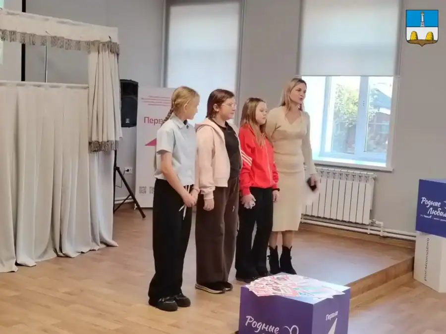 Четыре девочки и женщина стоят на сцене рядом с кукольной ширмой.