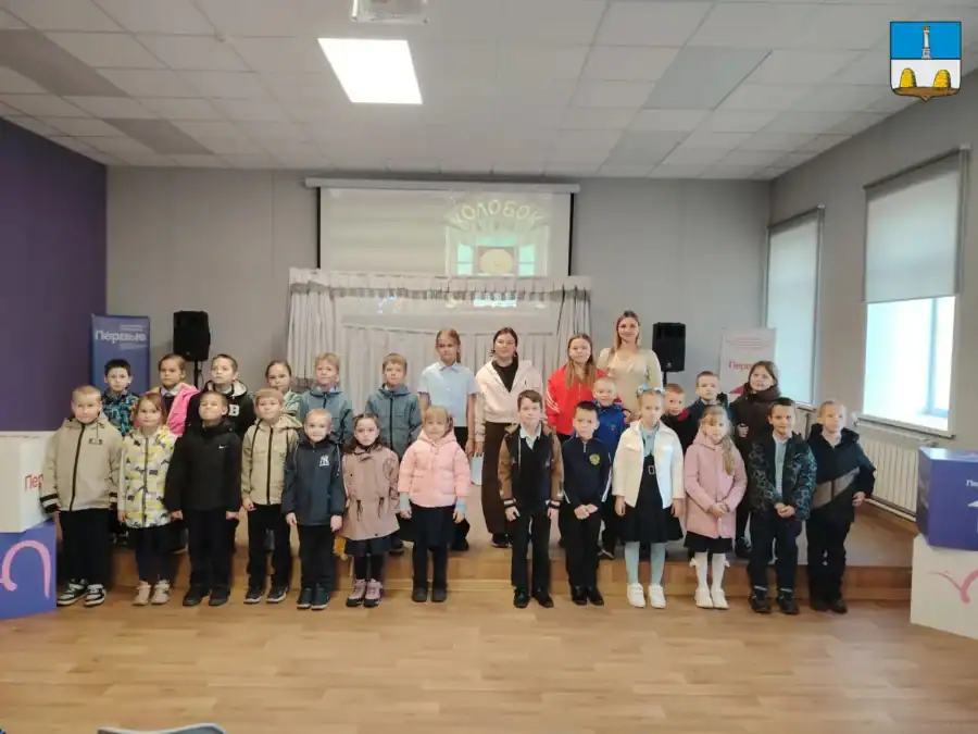 Дети и взрослые позируют группой перед сценой кукольного театра.