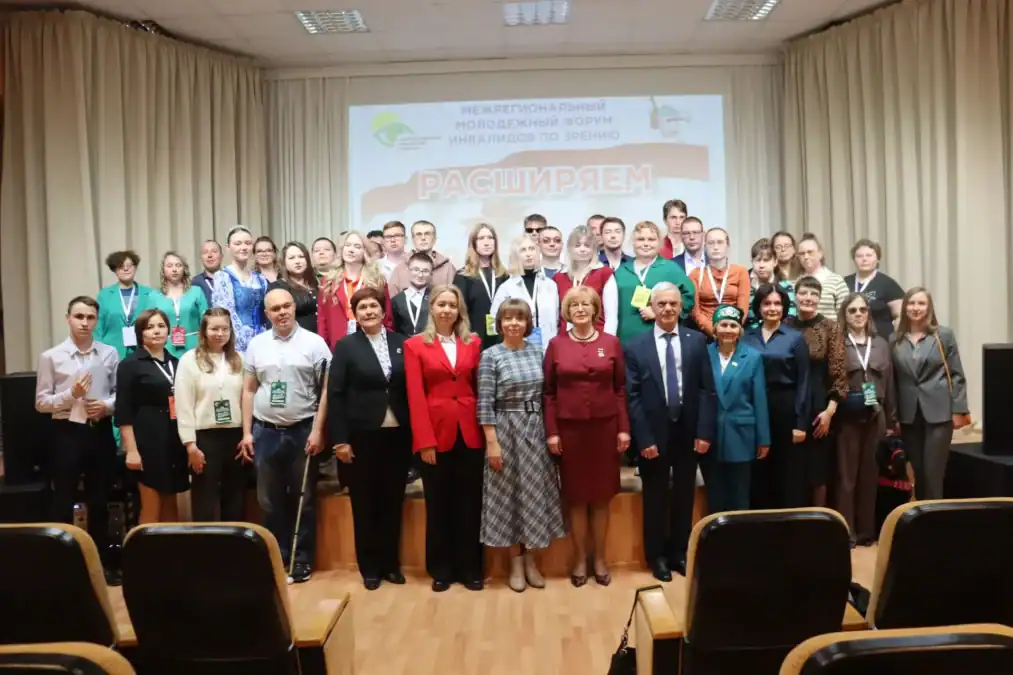 Участники форума позируют в зале на фоне экрана с названием мероприятия.