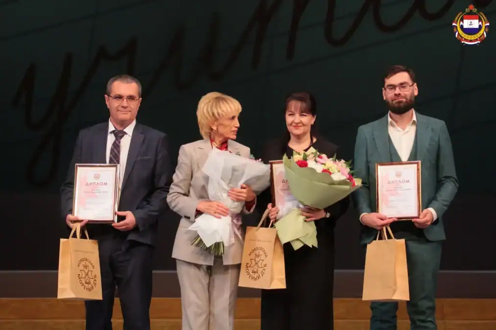 Четверо участников на сцене с дипломами, букетами и подарочными пакетами.