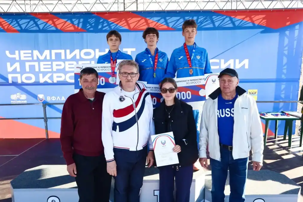 Медалисты с наградами стоят на пьедестале вместе с организаторами.