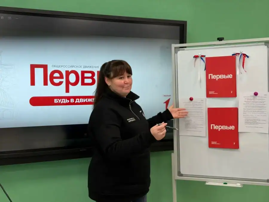 Женщина у интерактивного экрана показывает материалы на стенде «Движения Первых».