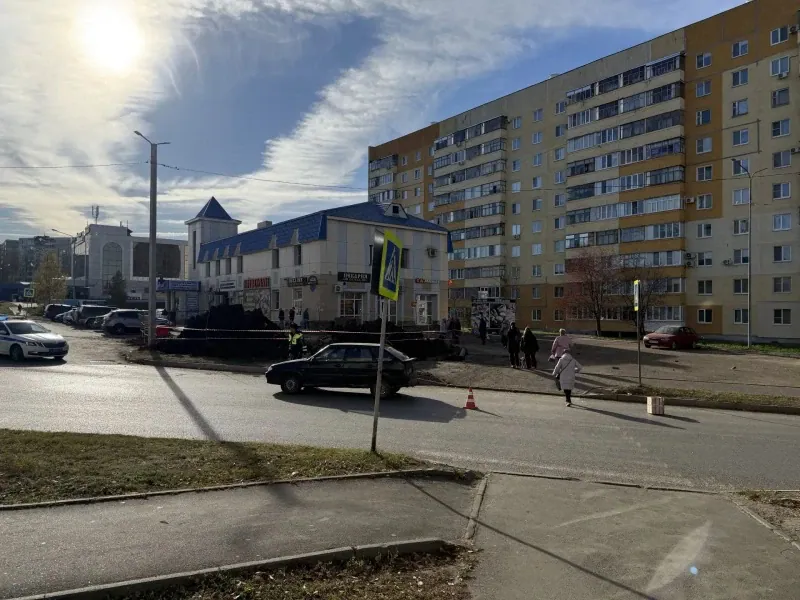 На городской улице у пешеходного перехода стоят автомобиль и несколько людей.