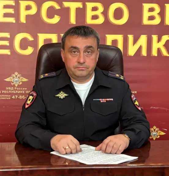Сотрудник полиции в форме сидит за столом с документами.