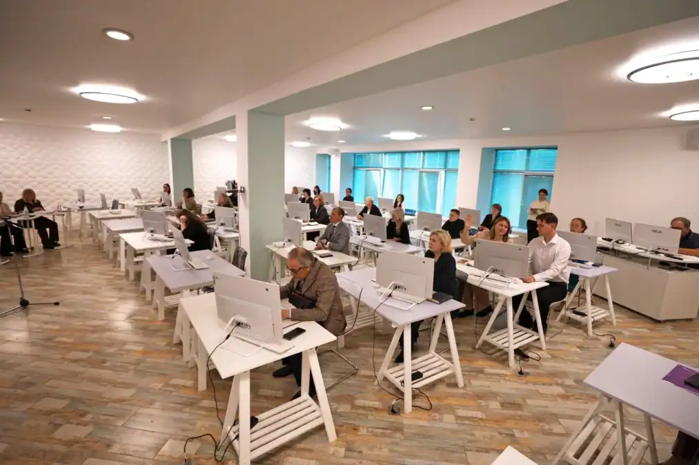 Участники заседания работают за компьютерами в просторной аудитории.