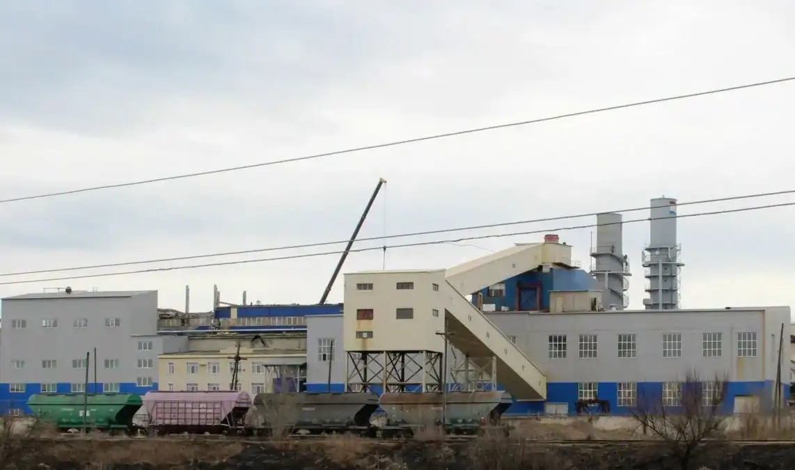 Корпуса сахарного завода с железнодорожными вагонами у производственной площадки.