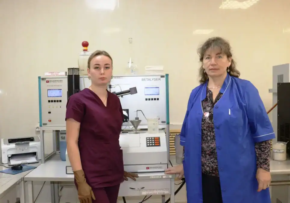 Две сотрудницы стоят рядом с лабораторным оборудованием в производственном помещении.