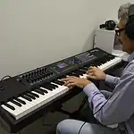 Мужчина в наушниках играет на электронном синтезаторе.