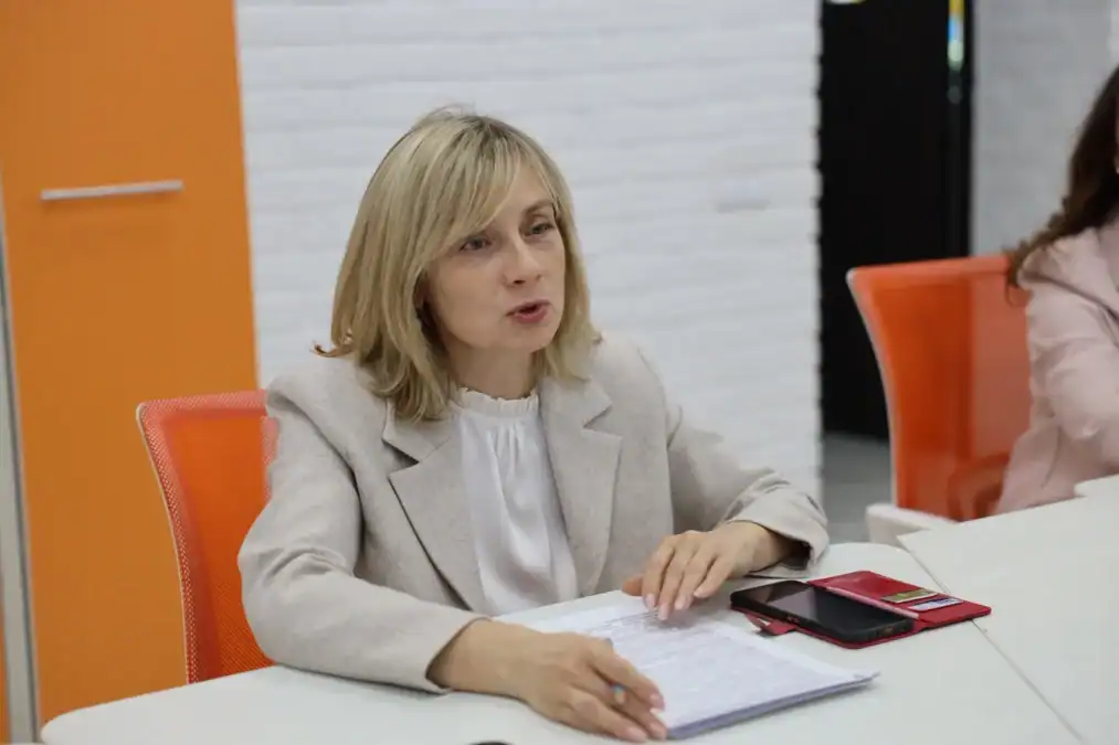 Женщина делает записи в блокноте за столом в аудитории.