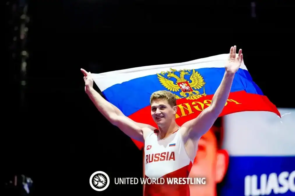 Спортсмен в форме Russia держит над головой российский флаг.