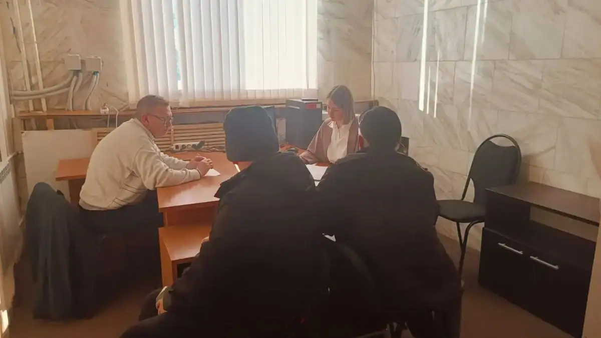 Четыре человека находятся на приеме в кабинете за рабочим столом.