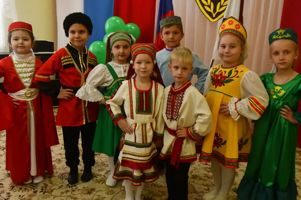 Дети в ярких национальных костюмах позируют в помещении.