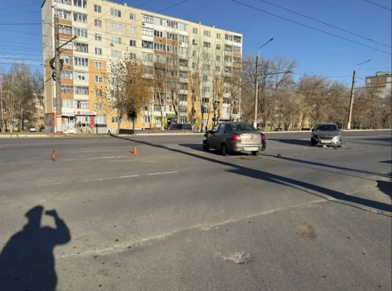 Два автомобиля стоят на широкой проезжей части рядом с дорожными конусами.