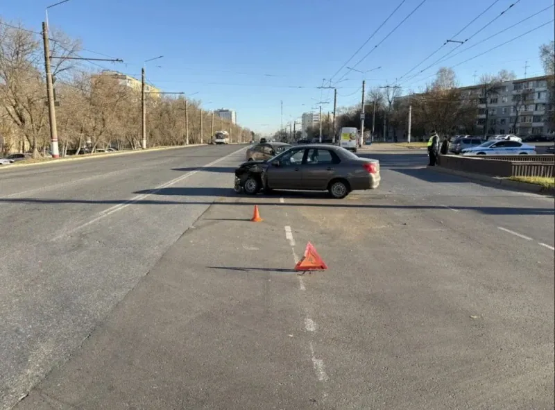 Седан с повреждённой передней частью стоит у конуса и знака аварийной остановки.