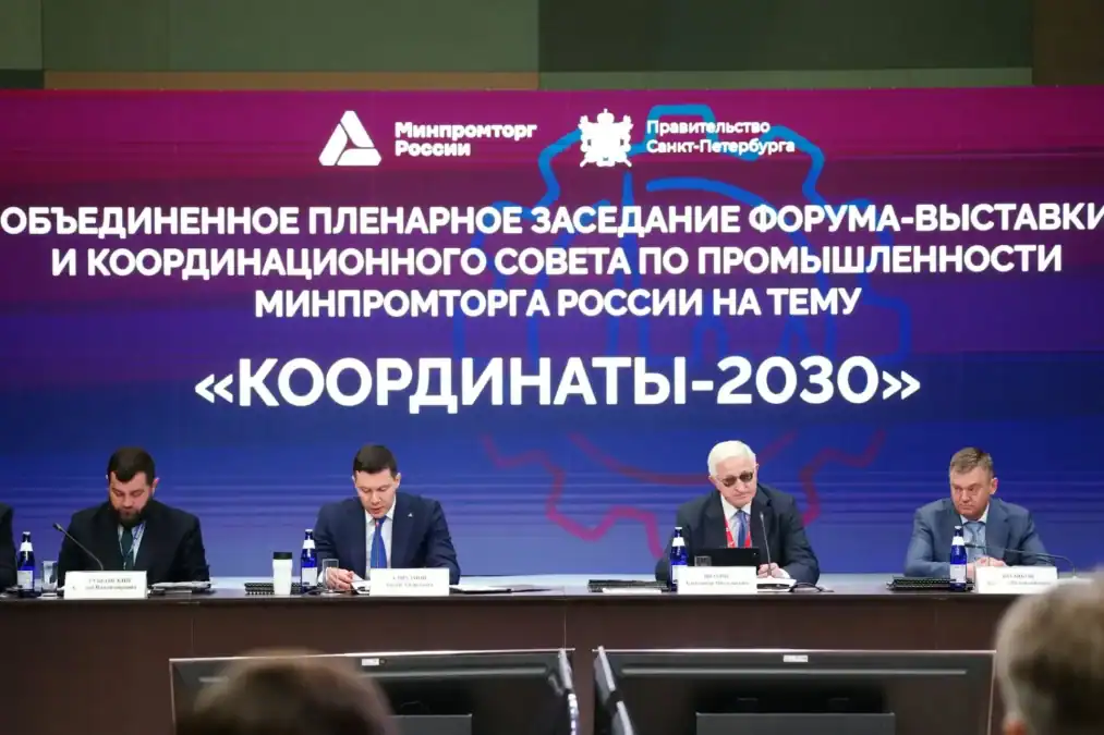 Четверо мужчин выступают на пленарном заседании перед тематическим баннером.