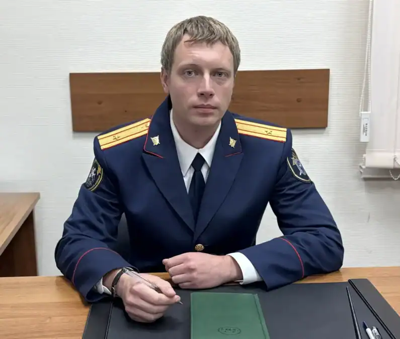 Сотрудник в форменном кителе сидит за рабочим столом в кабинете.