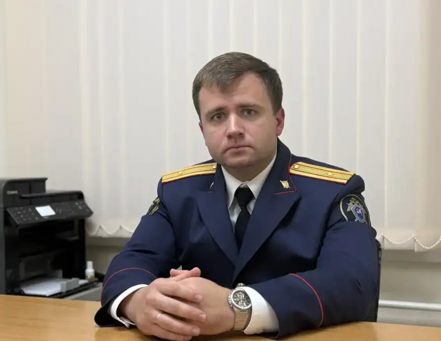 Сотрудник в форменном кителе сидит за столом в служебном кабинете.