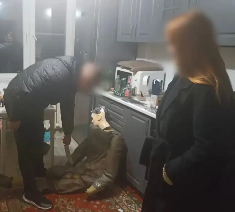 Мужчина в кухне указывает на пол рядом с сидящим на полу человеком.