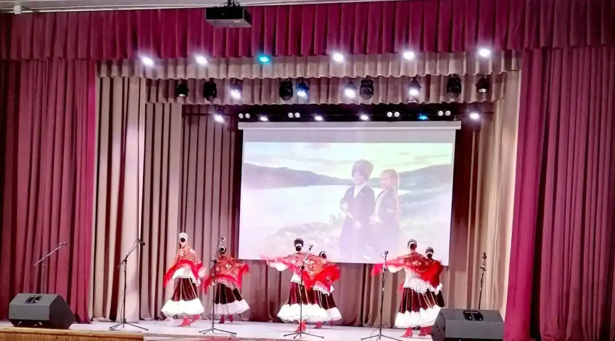 Танцовщицы в красных костюмах исполняют номер с веерами на сцене.
