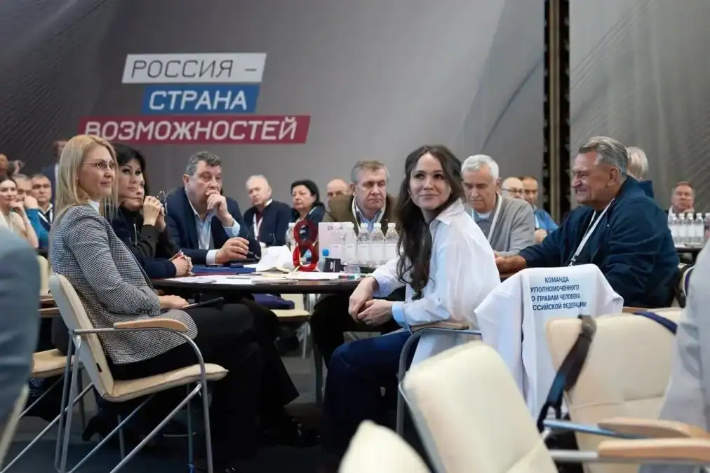 Участники семинара сидят за столом на фоне надписи «Россия — страна возможностей».
