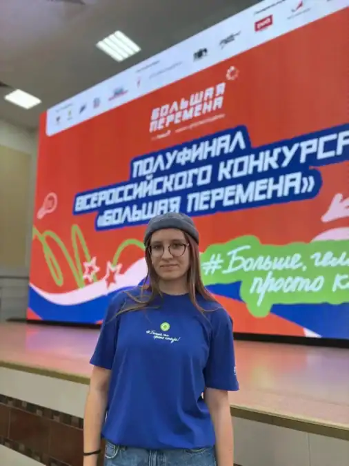 Участница в синей футболке стоит перед экраном полуфинала конкурса «Большая перемена».
