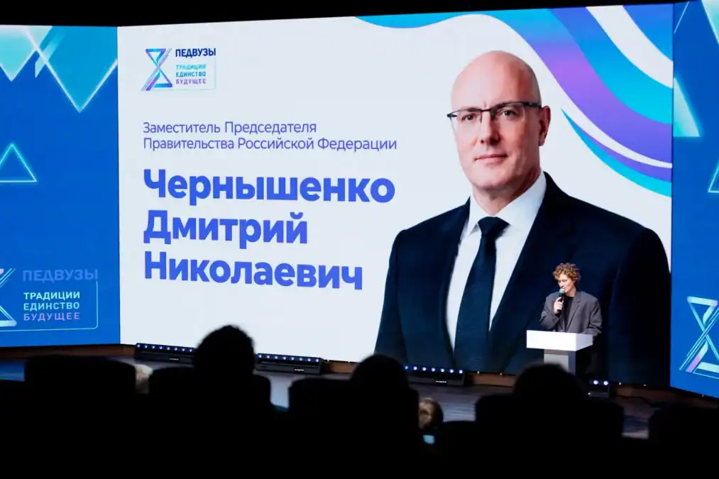 Спикер выступает перед экраном с портретом Дмитрия Чернышенко.