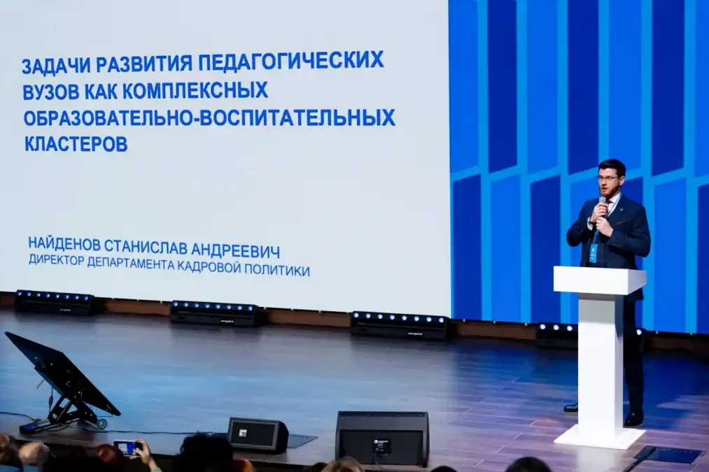 Мужчина выступает с трибуны перед слайдом о развитии педагогических вузов.