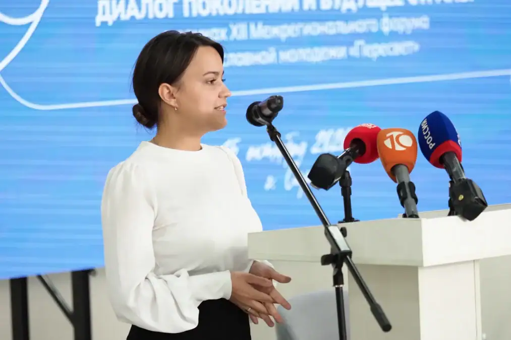 Женщина выступает с трибуны перед несколькими микрофонами.