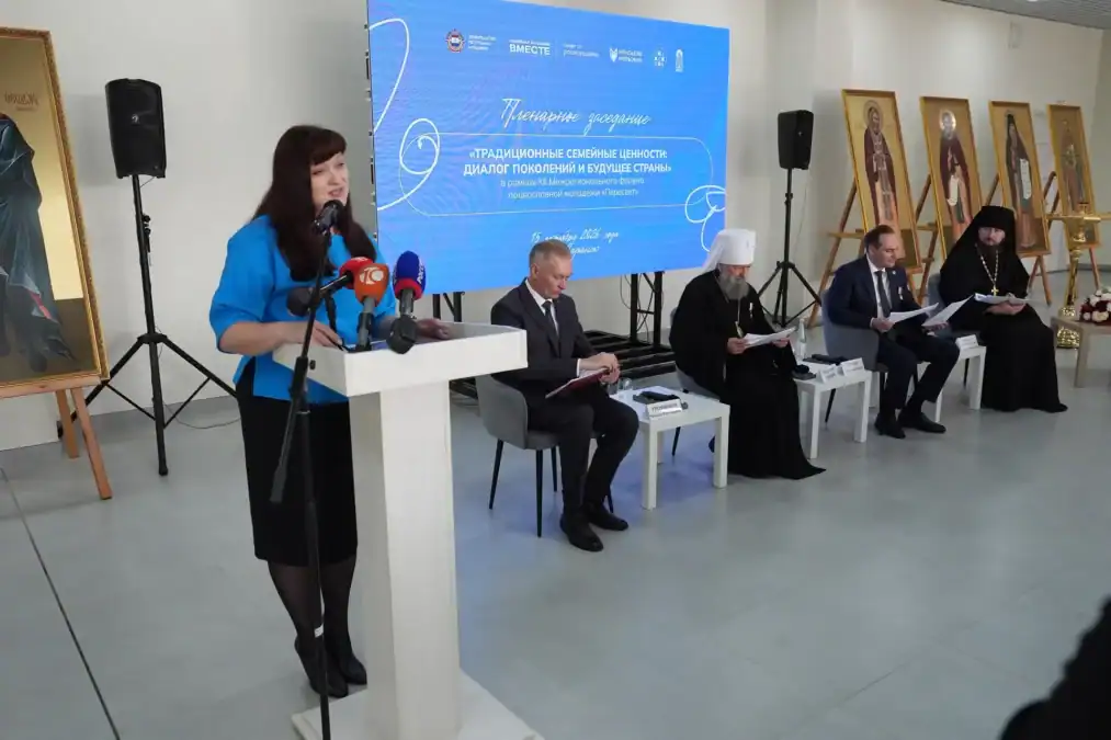 Женщина выступает у трибуны перед участниками пленарной дискуссии.