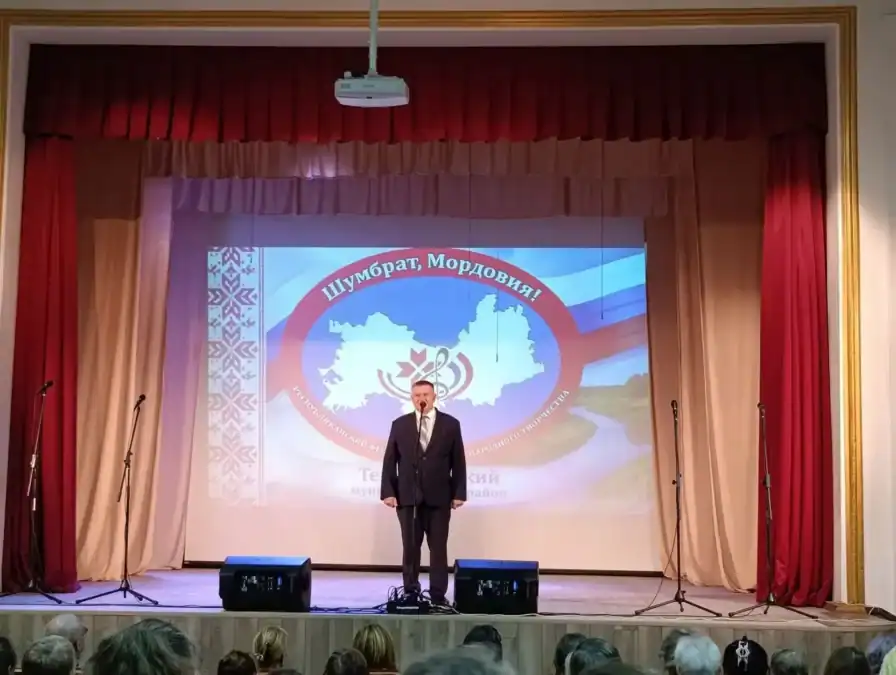 Мужчина выступает с микрофоном на сцене перед зрителями.