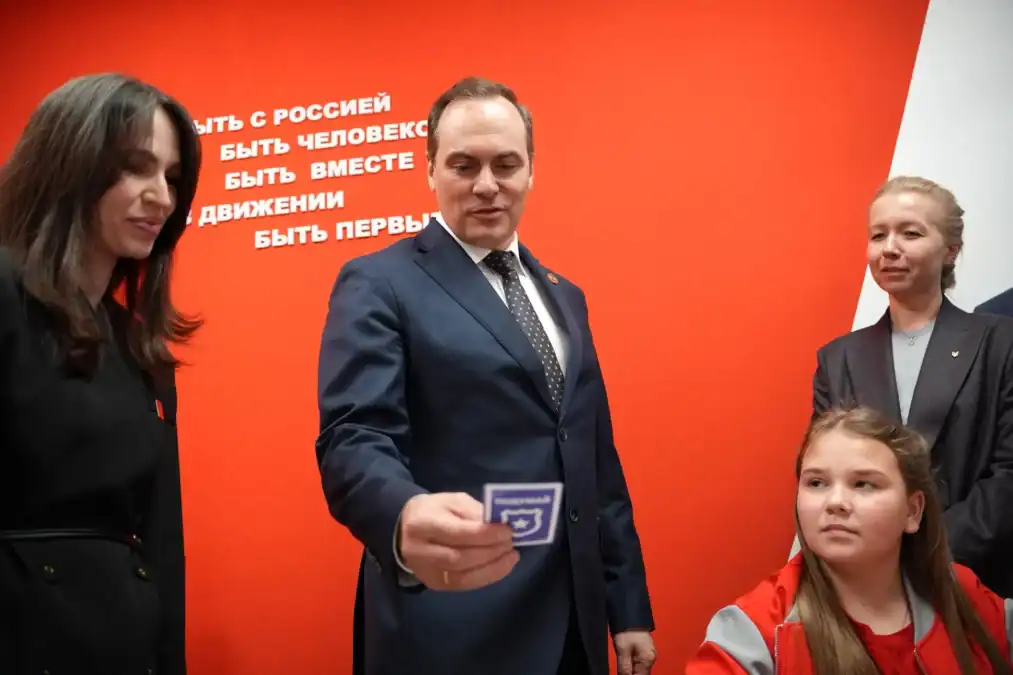 Мужчина в костюме показывает девочке небольшую карточку.