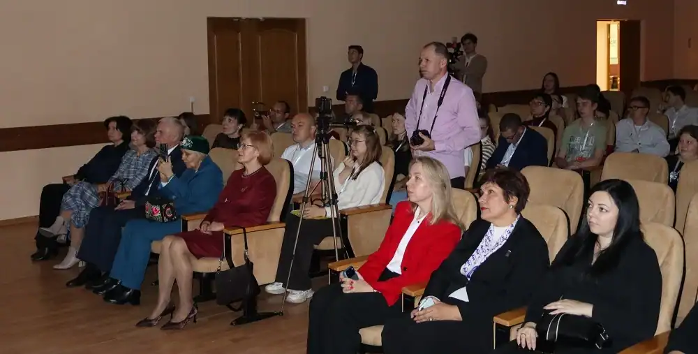 Участники форума сидят в зрительном зале, рядом установлена камера на штативе.
