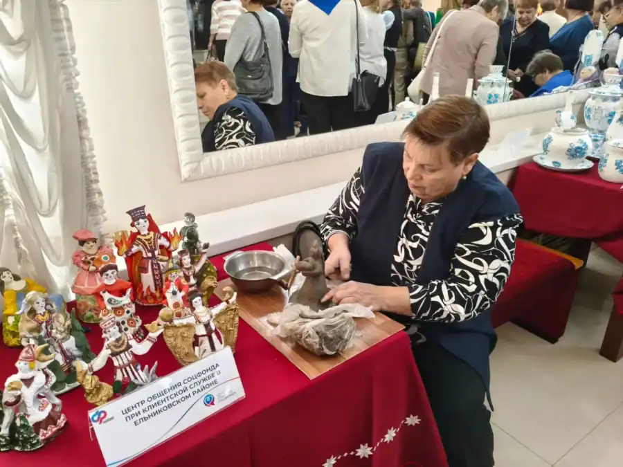 Женщина проводит мастер-класс за столом с фигурками ручной работы.