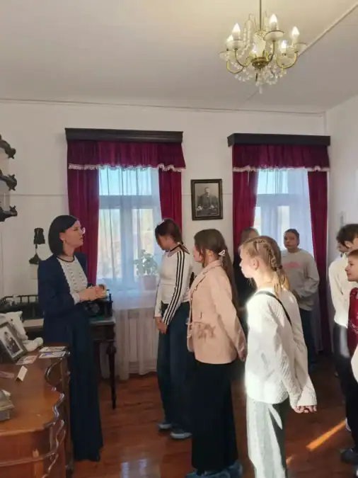 Экскурсовод рассказывает школьникам о предметах в музейной комнате.