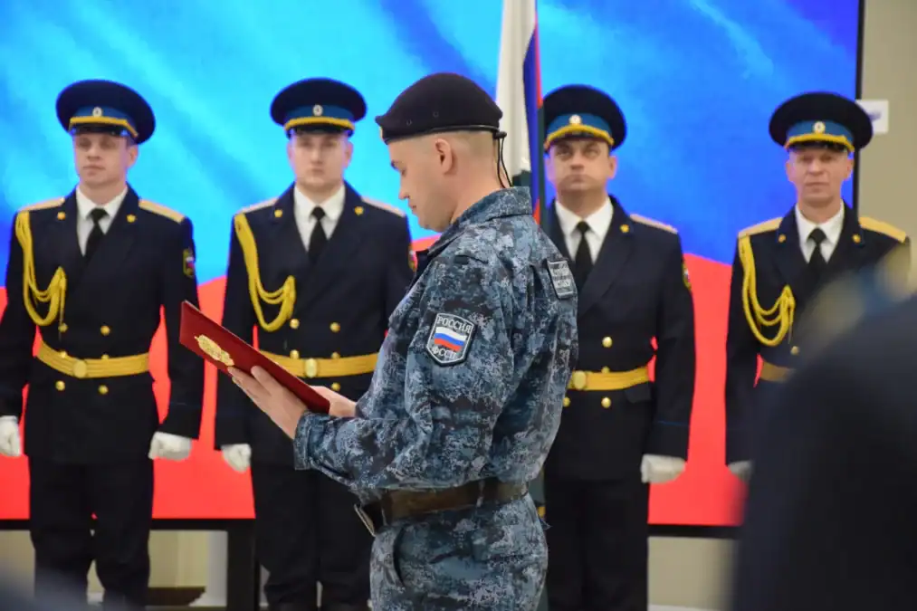 Сотрудник в камуфляжной форме читает текст перед почётным караулом.
