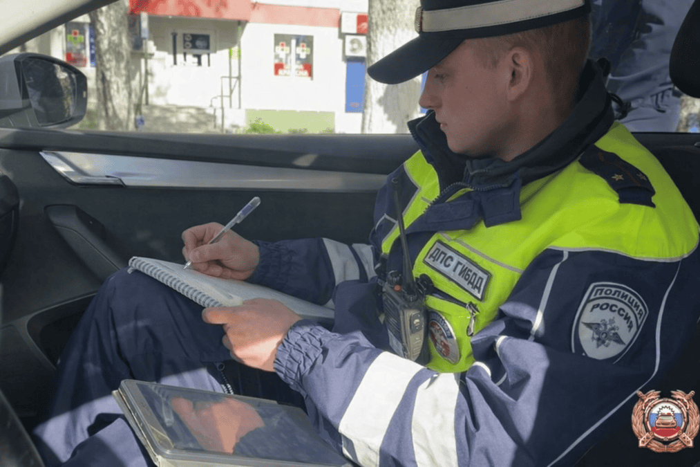 Инспектор ДПС заполняет документы в салоне автомобиля.