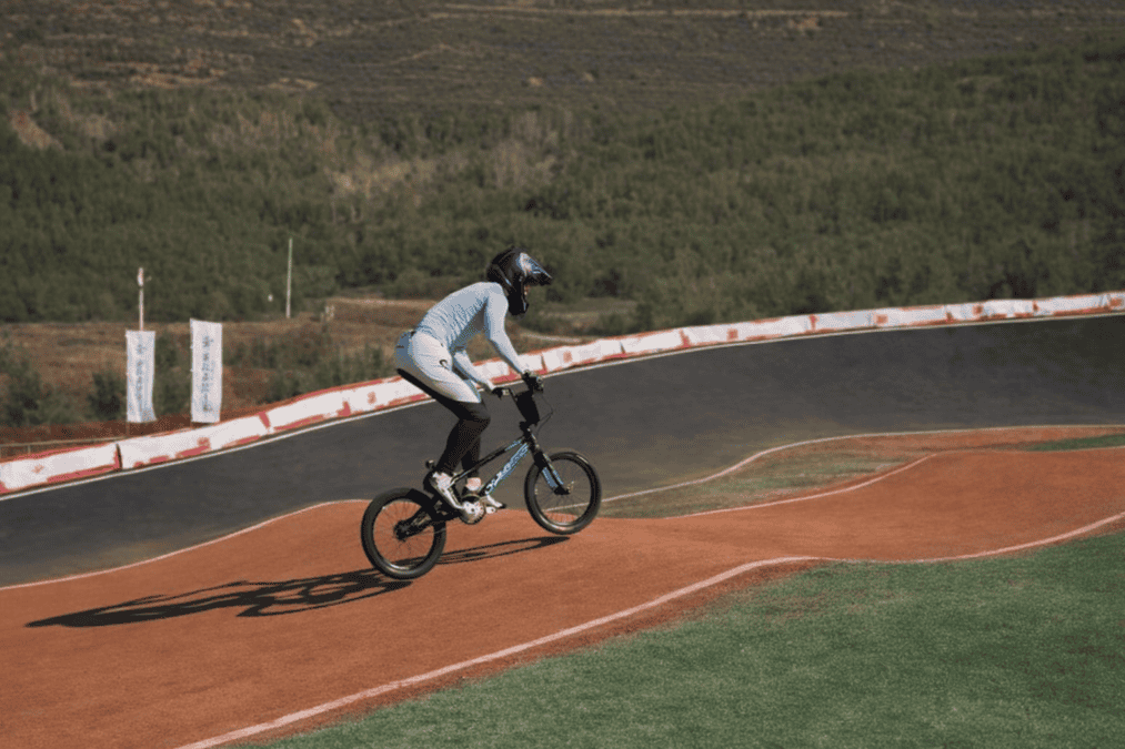 Райдер в шлеме едет на BMX-велосипеде по виражу трассы.