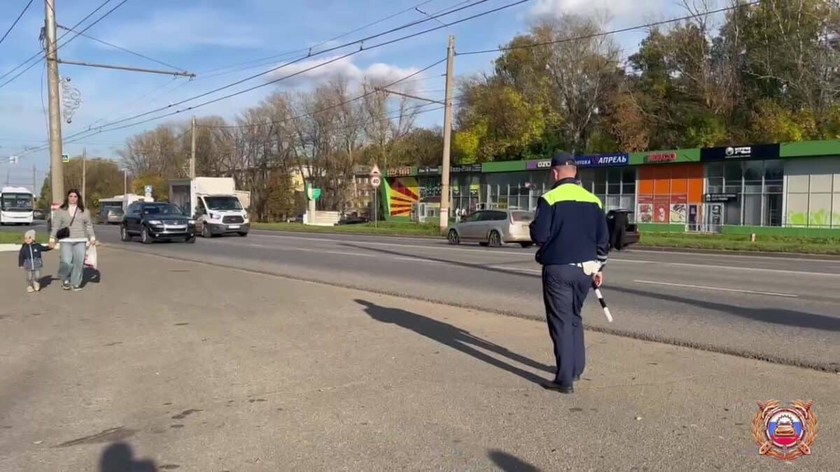 Инспектор ДПС регулирует движение на городской дороге рядом с пешеходами.