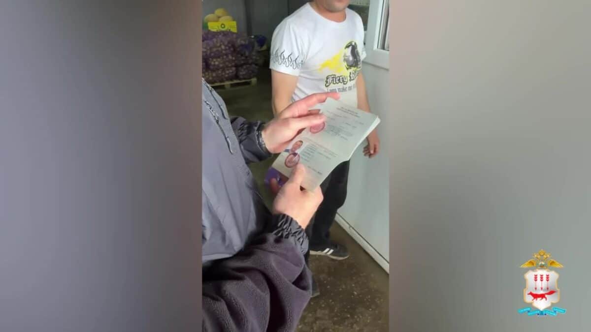 Полицейский рассматривает документ в руках рядом с мужчиной у входа.