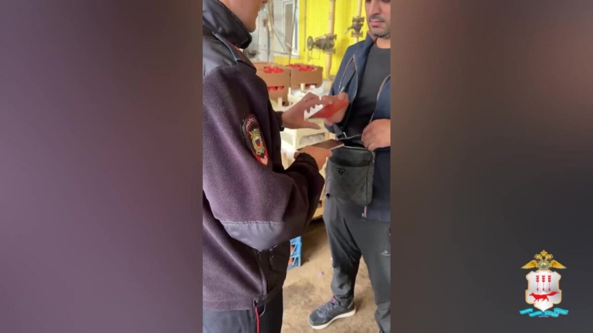 Сотрудник полиции проверяет документы у мужчины в производственном помещении.