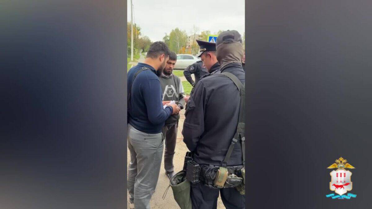 Полицейские проверяют документы у двух мужчин возле дороги.