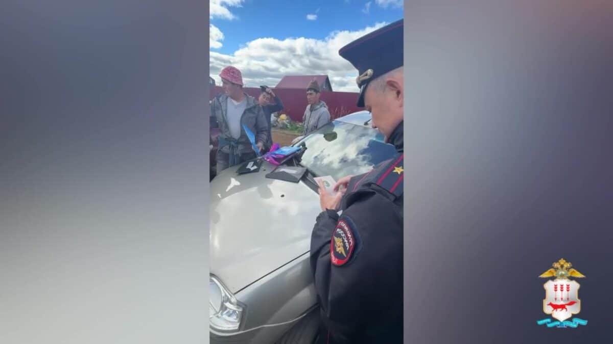 Полицейский записывает сведения у автомобиля в присутствии нескольких мужчин.