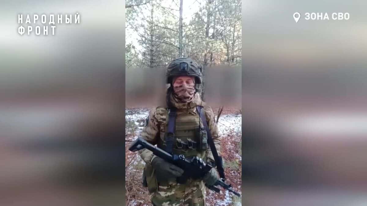 Военнослужащий в защитном снаряжении держит оружие в заснеженном лесу.