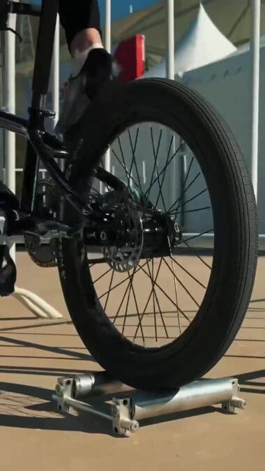 Заднее колесо BMX-велосипеда установлено на роликовый тренажёр.