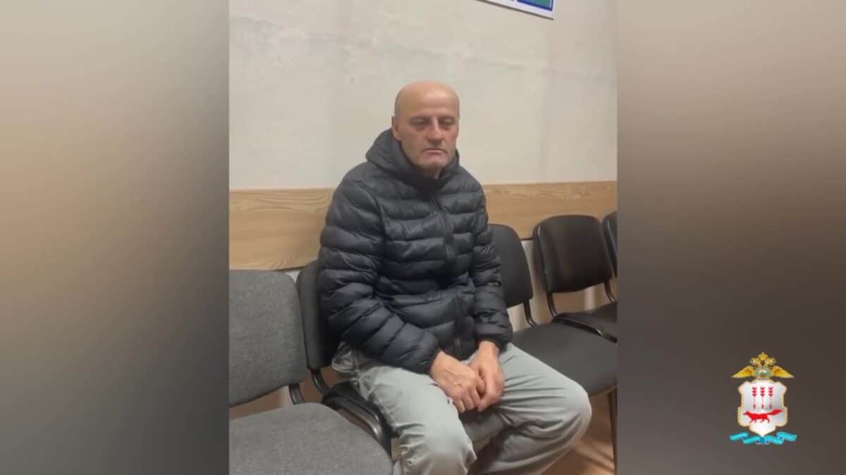 Мужчина в чёрной куртке сидит на стульях в помещении.