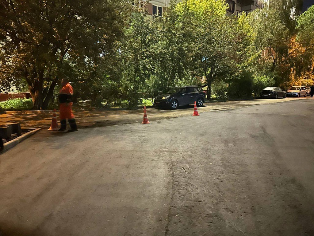 Строительство новой асфальтированной тротуарной дорожки рабочими в оранжевой спецодежде